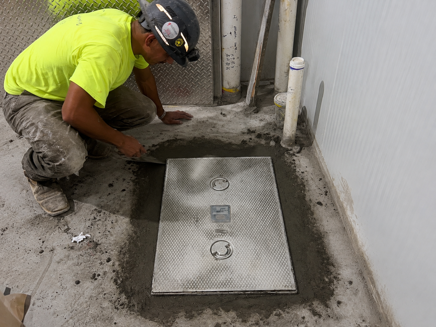 Webster & Sons technician finishing concrete around commercial floor cleanout access cover at Olive Garden Selma NC
